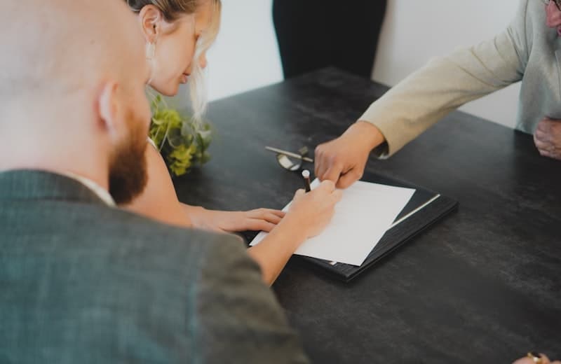An older couple signing documents with an advisor across the table